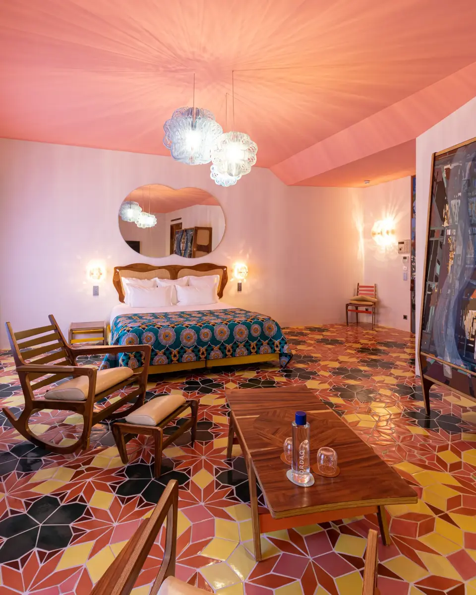 Chambre rose à L'Arlatan avec une table basse et deux fauteuils en premier plan et un lit en arrière plan